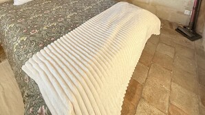 Une chambre à coucher avec un lit, une fenêtre, une table de chevet et un ventilateur de plafond.