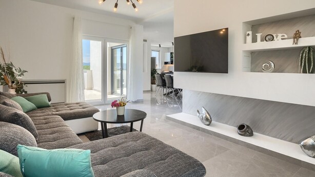 Una sala de estar moderna con un sofá, una mesa de centro y un televisor montado en la pared.