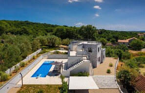 Enjoy the rooftop pool and outdoor seating amidst lush greenery with views of the surrounding landscape.