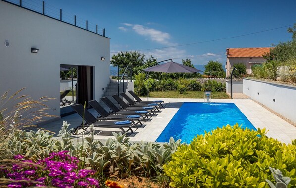 Relax by the pool surrounded by lush gardens and lounge chairs.