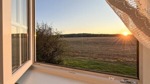 A window view of a field at sunset with a clear sky. - 1 bedroom cozy home in Vormsund (Vormsund)