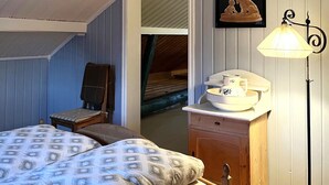 A cozy room with two beds, a chair, a nightstand with a lamp, and a framed picture on the wall. - 1 bedroom cozy home in Vormsund (Vormsund)
