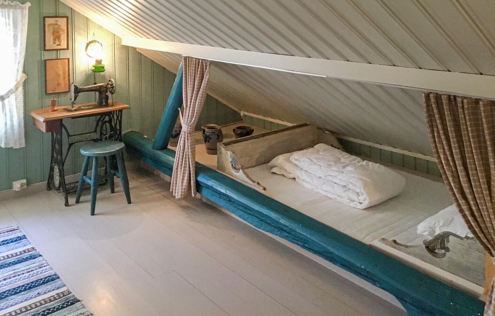 A small, cozy attic bedroom with a single bed, a desk, and a chair.