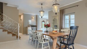 Un coin repas avec une table en bois, des chaises blanches et noires, et un vase rempli de fleurs rouges.