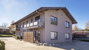 A two-story residential building with a balcony on the upper floor, a garage door, and a fenced yard. - Yurali apartment is located within walking distance to the town centre. (Jindabyne)