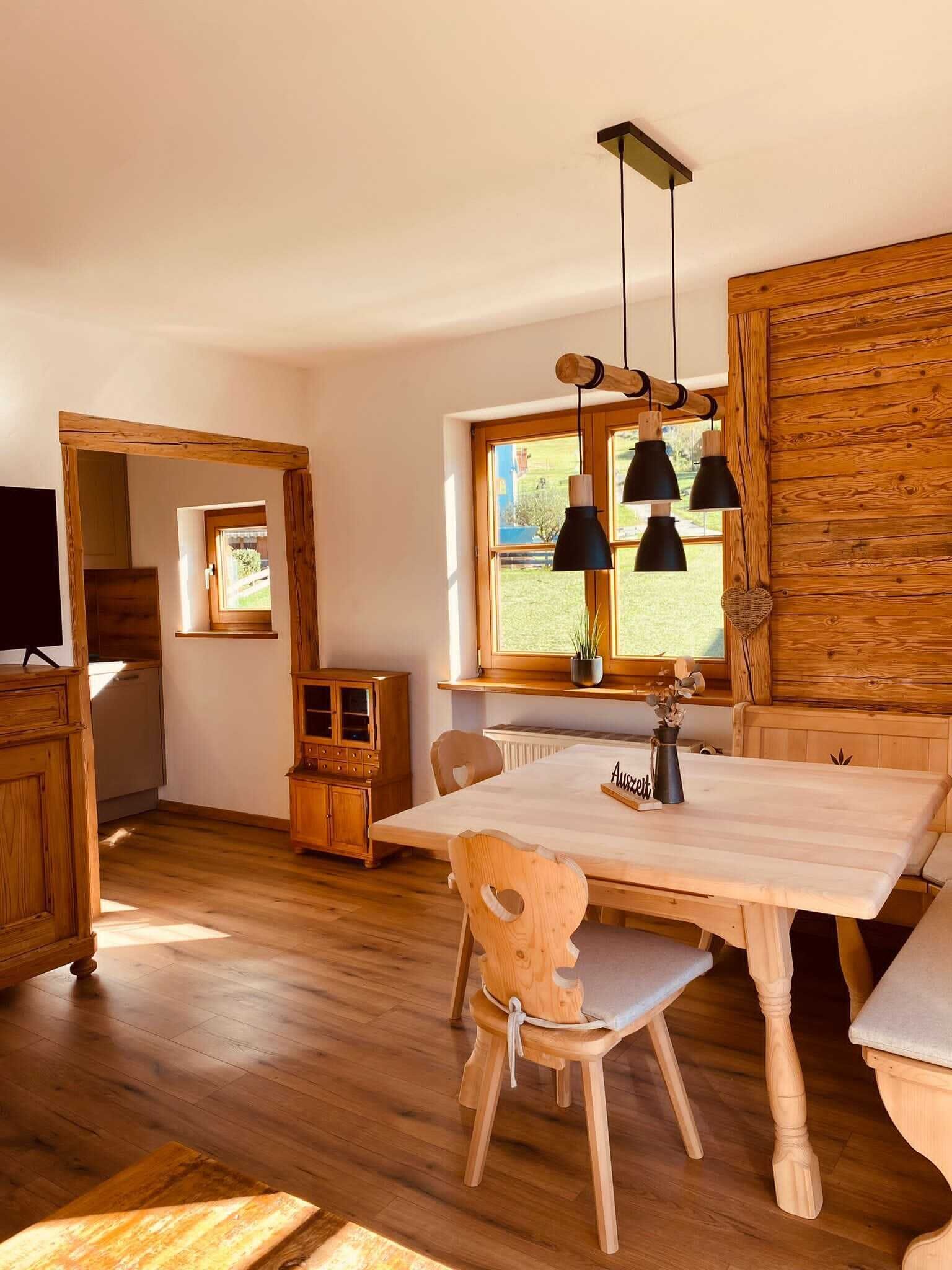 A wooden dining area with a table, chairs, and pendant lights.