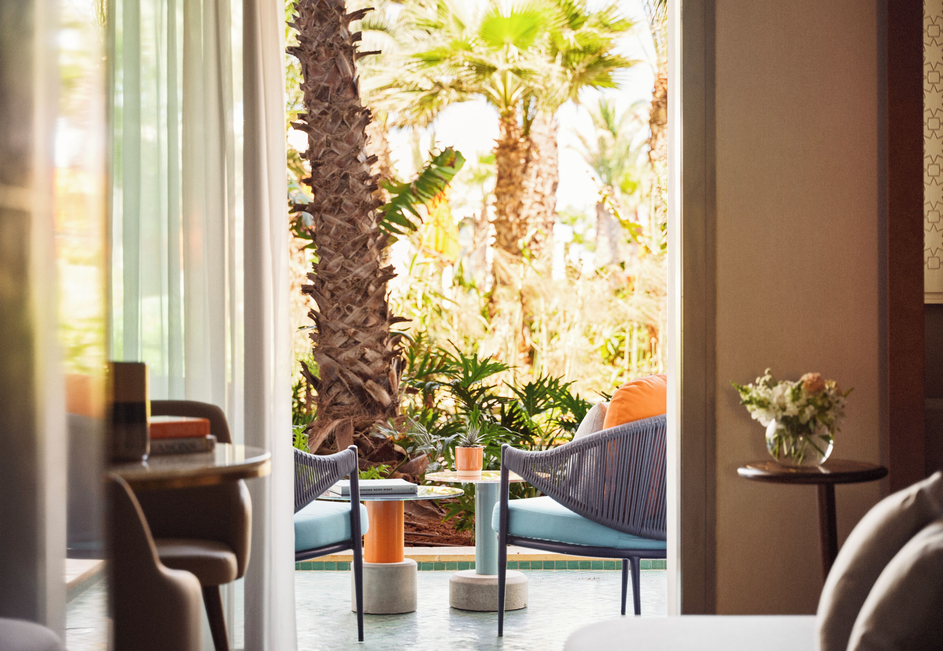 An indoor seating area with a view of a tropical garden outside.