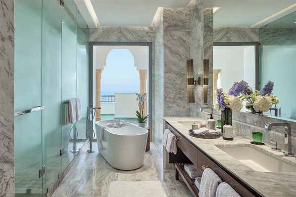 A modern bathroom with a freestanding bathtub, a large mirror, and a view of a building through an archway.