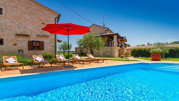 A pool area with lounge chairs and a red umbrella. - Beautiful home in Rovinj (Rovinj)