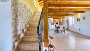 A staircase with stone walls, a wooden ceiling, and a dining area with chairs and a table. - Beautiful home in Rovinj (Rovinj)