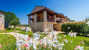 A two-story stone house with a balcony, surrounded by a well-maintained garden with white and pink flowers. - Beautiful home in Rovinj (Rovinj)