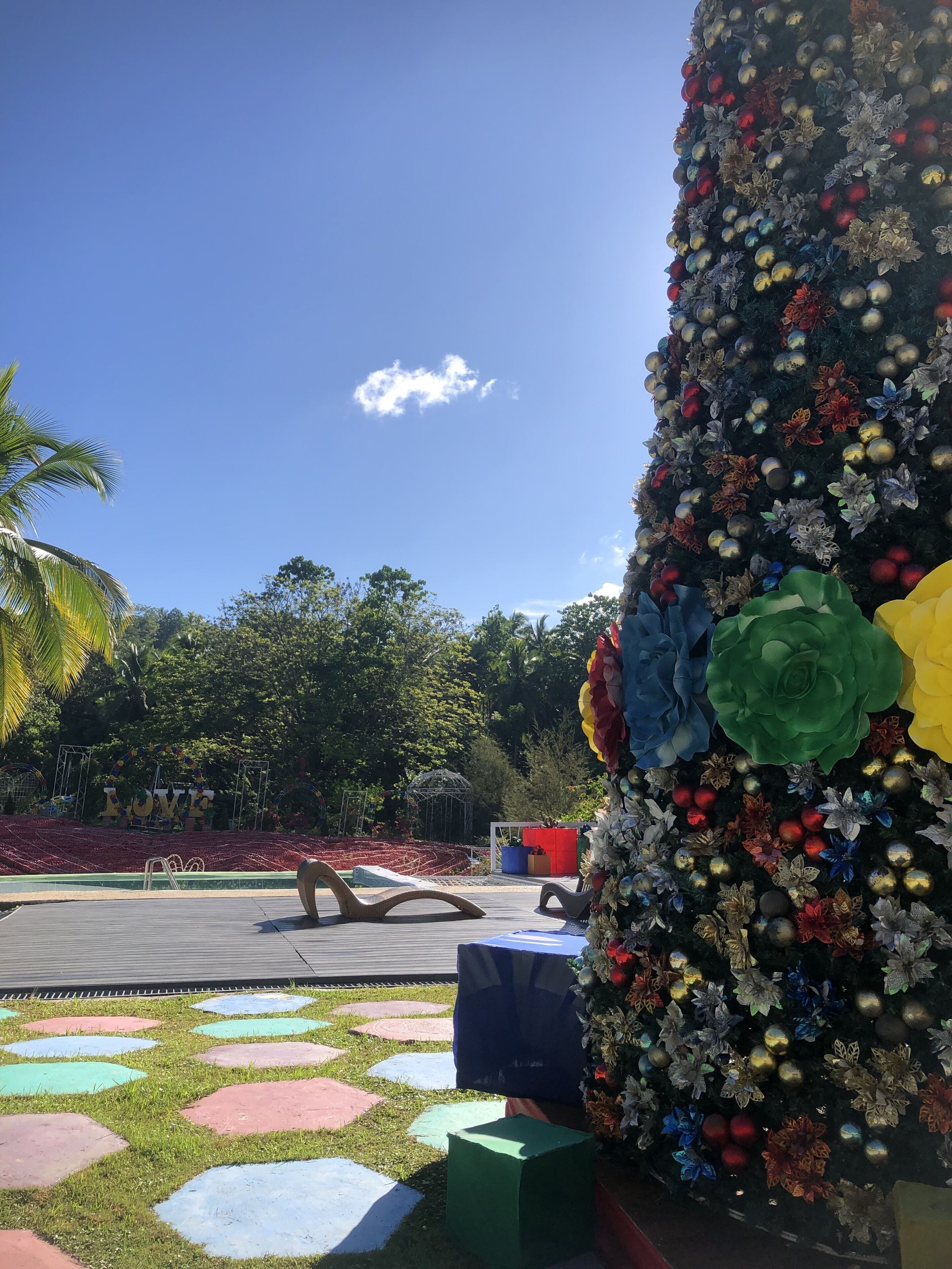 Un espacio exterior decorado con un escenario, asientos y un gran arreglo floral.