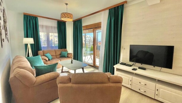 Ein Wohnzimmer mit Sofa, Couchtisch, Fernseher und Vorhängen.