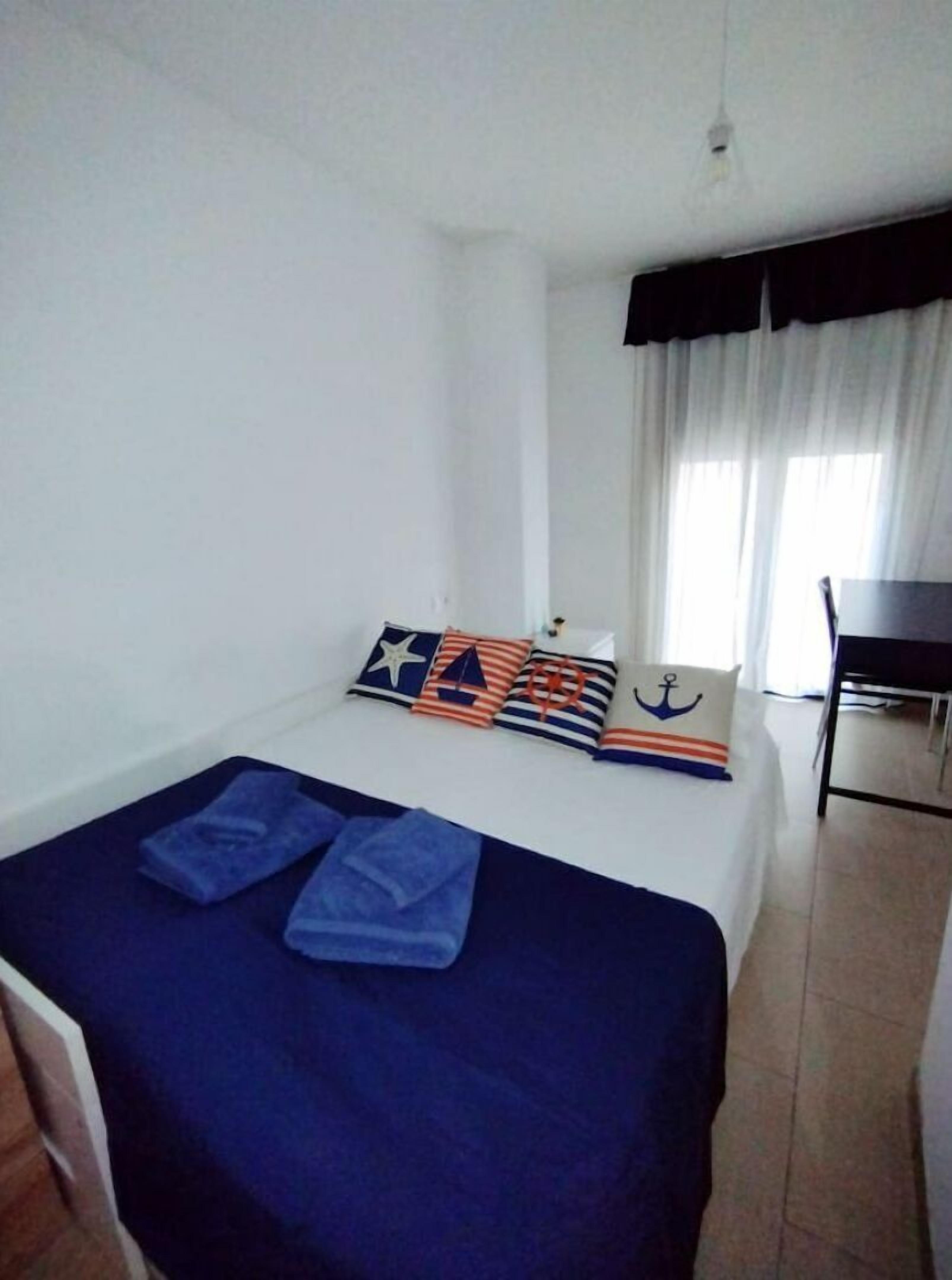 Hotellihuone, jossa on sänky, tuoli ja työpöytä.