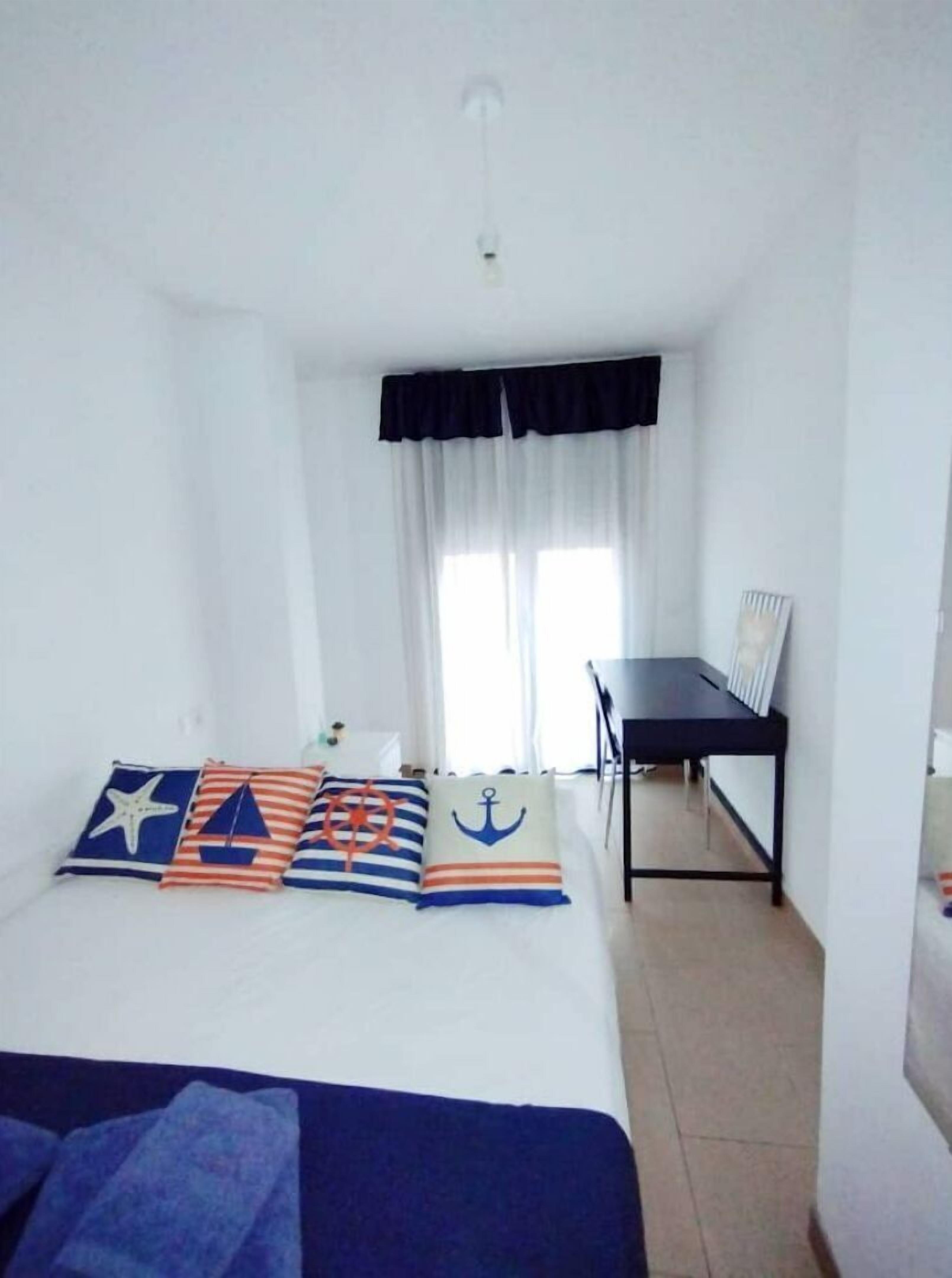 A bedroom with a bed, a desk, and a chair.