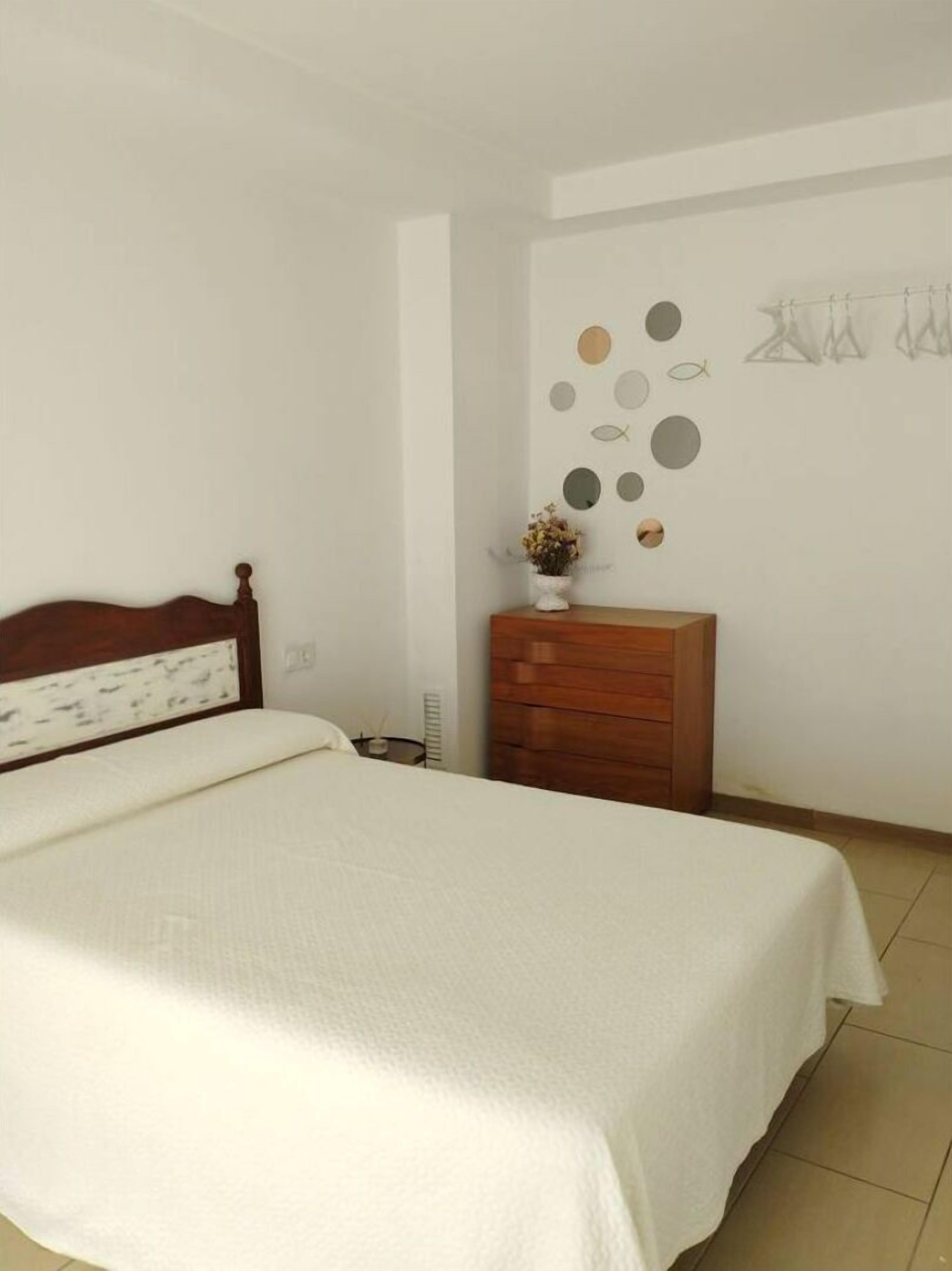Un dormitorio con una cama grande, un aparador de madera y un muro decorado con adornos circulares y con forma de pez.