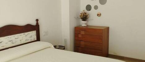 Un dormitorio con una cama grande, un aparador de madera y un muro decorado con adornos circulares y con forma de pez.