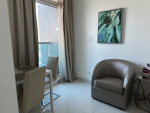 Relax in a serene space with a comfortable sofa, compact dining area, and a large window offering a view of the outdoors.