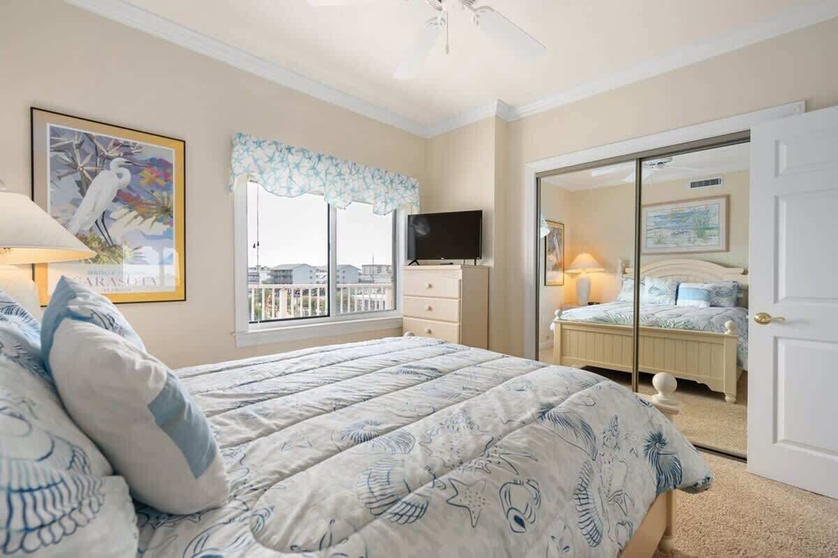 Una camera da letto con un letto, una televisione, una finestra vista e una porta che dà su un'altra stanza.