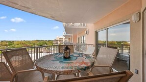 Een balkon met een ronde tafel, stoelen en een lantaarn.