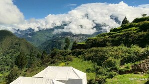 A tent in a lush green valley with mountains in the background. - Khaltaal Camp And Resorts (Chamoli)