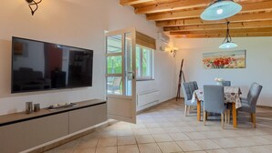 A modern kitchen with a TV, dining area with chairs and a table, and a painting on the wall. - Gorgeous home in Pula (Pula)