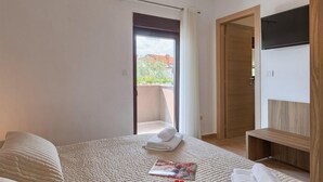 A bedroom with a bed, a bedside table, a TV mounted on the wall, and a door leading to a balcony. - Gorgeous home in Pula (Pula)