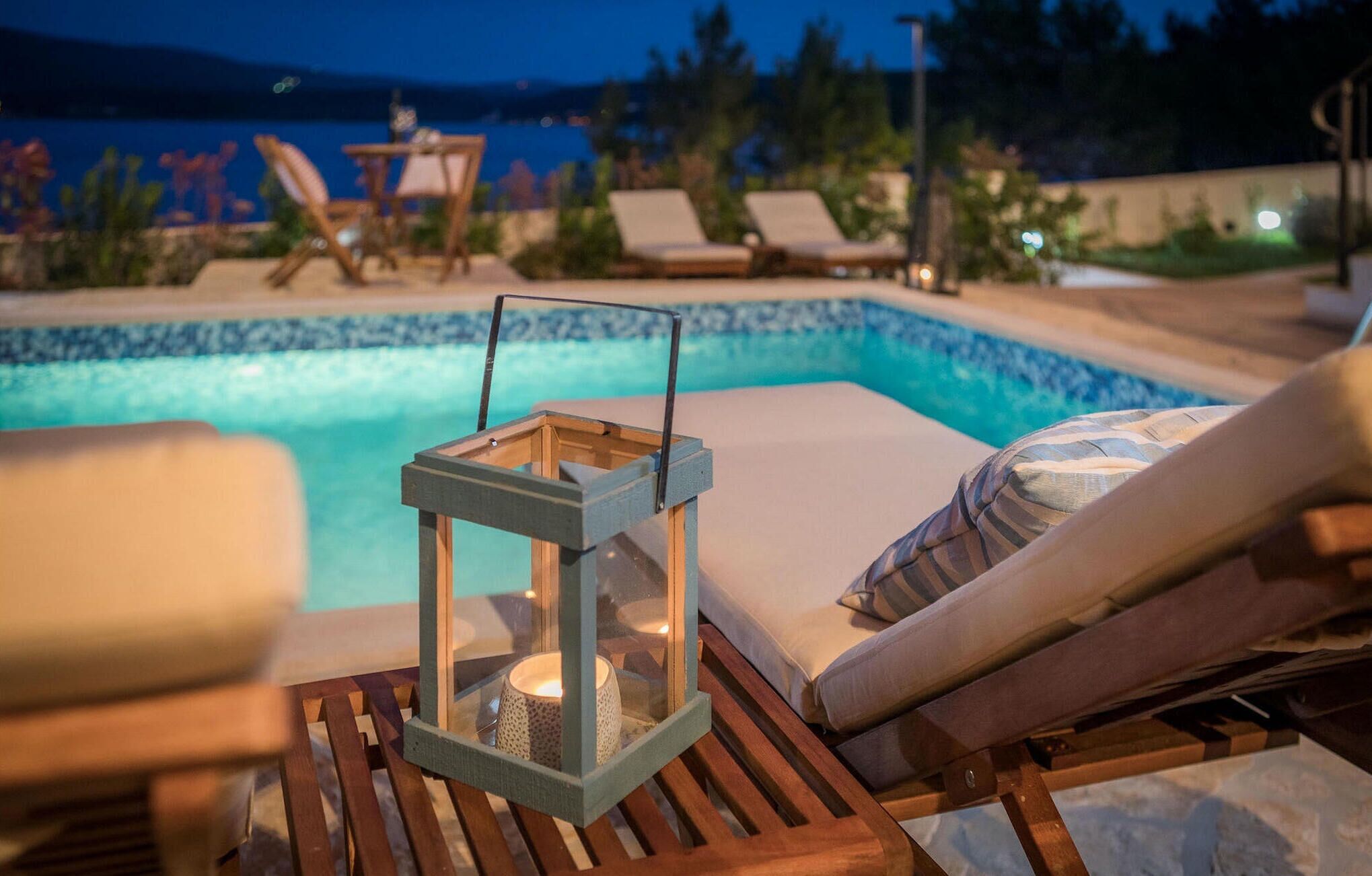 A poolside area with lounge chairs and a lantern.
