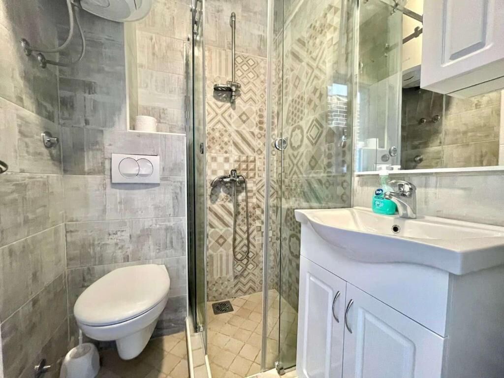A bathroom with a toilet, shower, and sink.