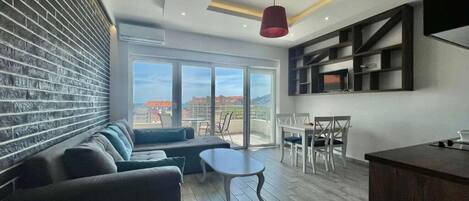 A modern living room with a sofa, a coffee table, and a dining area with a table and chairs.
