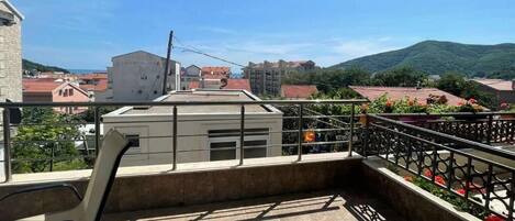 A balcony with a view of buildings and hills.