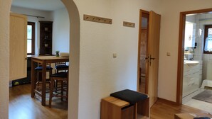Una habitación con un banco de madera, una mesita y un acceso a un baño.