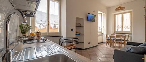 A modern kitchen with a large sink, a stove, and a dining area with a table and chairs.
