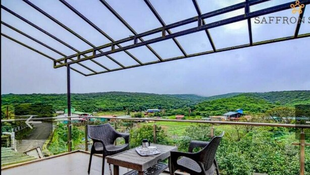 Ein Balkon mit Tisch und Stühlen mit Blick auf eine üppige, grüne Landschaft.