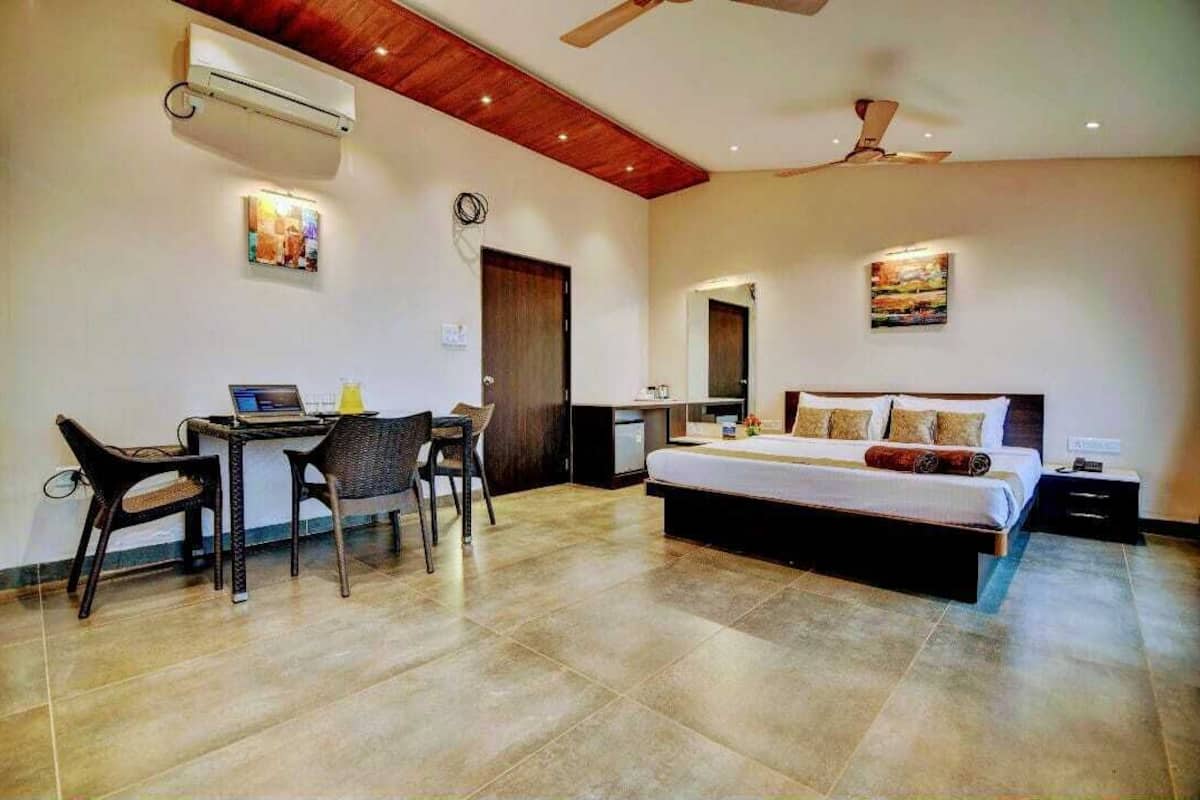 A modern bedroom with a large bed, a desk with a laptop, and a ceiling fan.