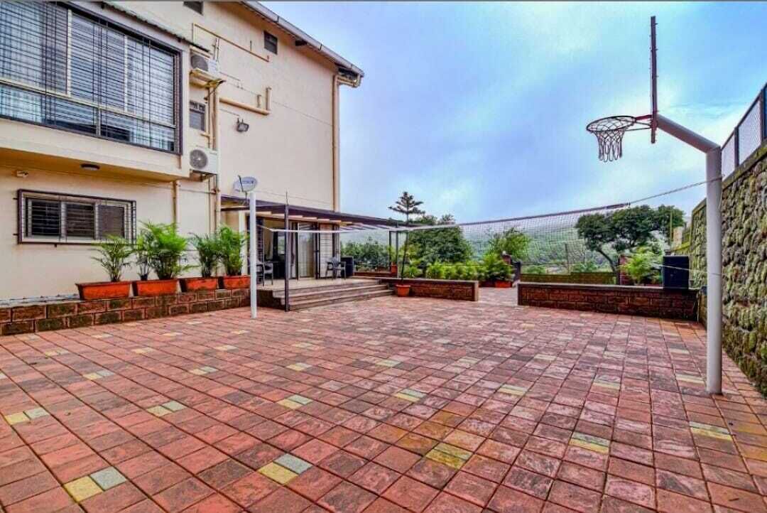 A basketball court with a net, potted plants, and a building in the background.