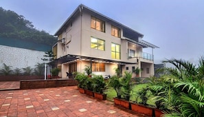 A two-story building with a covered patio area, multiple windows, and a balcony.