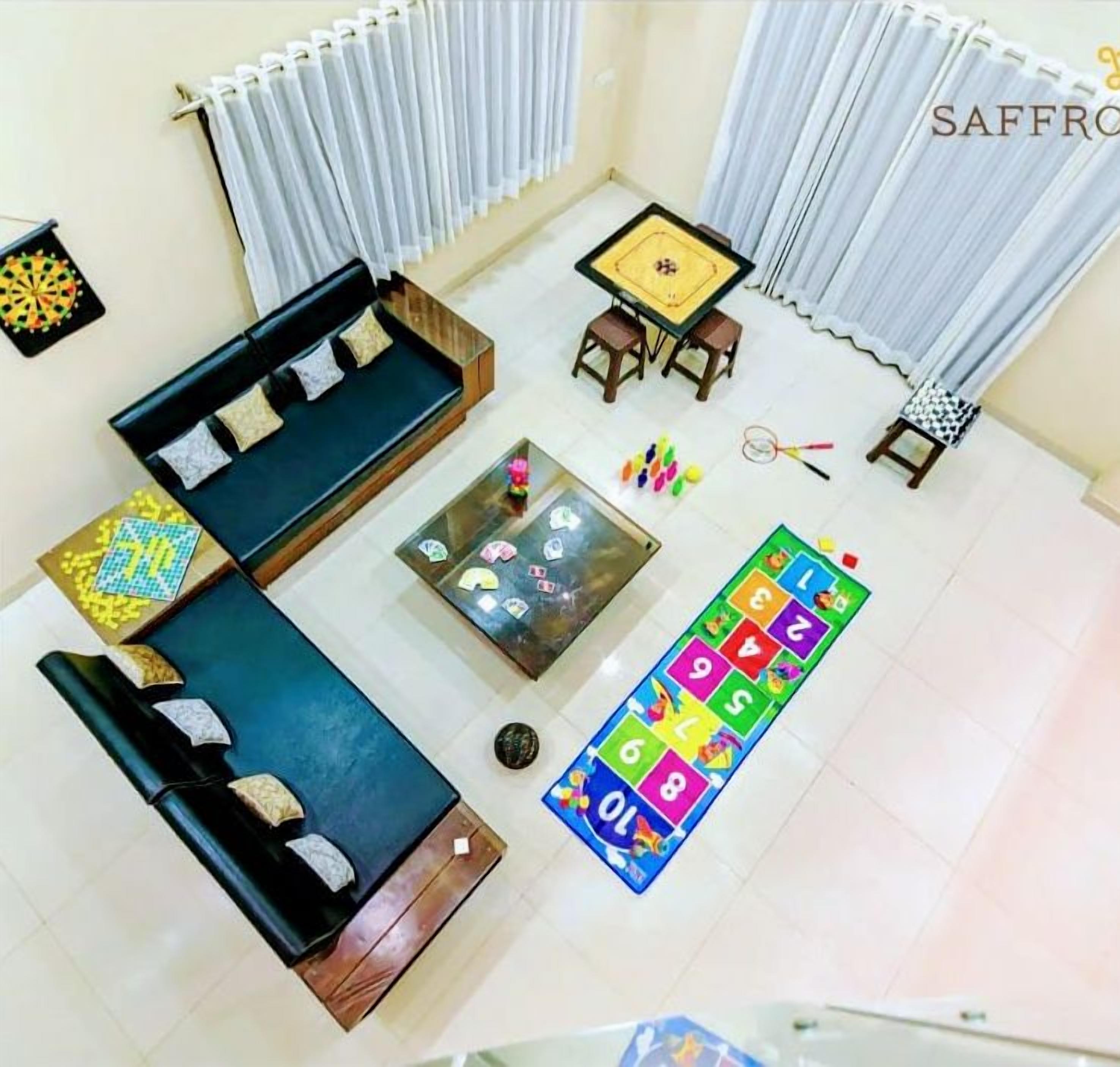 Une pièce comprenant un canapé, une petite table, un tapis de jeu et un jeu de fléchettes.