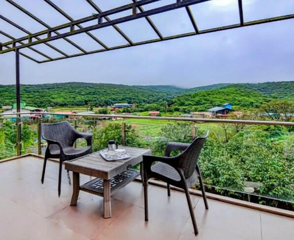 A balcony with a table and chairs, overlooking a lush green landscape.
