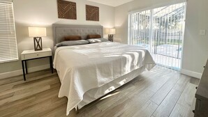A bedroom with a large bed, two bedside tables with lamps, a window with blinds, and a view of the outdoors. - Behemian 4Bd Villa w/ Pool at Solana Resort (Davenport)
