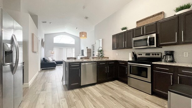 A modern kitchen with stainless steel appliances, dark cabinetry, and a central island. - Behemian 4Bd Villa w/ Pool at Solana Resort (Davenport)