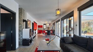 A modern living room with a black leather sofa, a dining area with a red table, and a kitchen with red cabinets. - Stunning home in Svetvincenat (Svetvincenat)