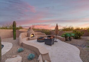 An outdoor patio with a built-in fire pit, seating, and a cactus in the background. - Luxury Retreat with Heated Pool in Scottsdale (Scottsdale)