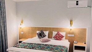 A hotel room with a large bed, a nightstand, an air conditioning unit, and a wall-mounted lamp. - SHAHEREZADE GARDEN (Bukhara)