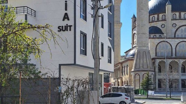 A building with 'CAPADOCIA SUIT' signage, a minaret, and a mosque with domes. - CAPPADOCIA SUIT RESIDENCE (Nevsehir)