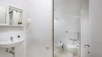 A modern bathroom with a sink, mirror, hairdryer, bidet, and toilet.
