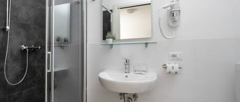 A modern bathroom with a glass shower enclosure, a white sink with a mirror above it, and a toilet.