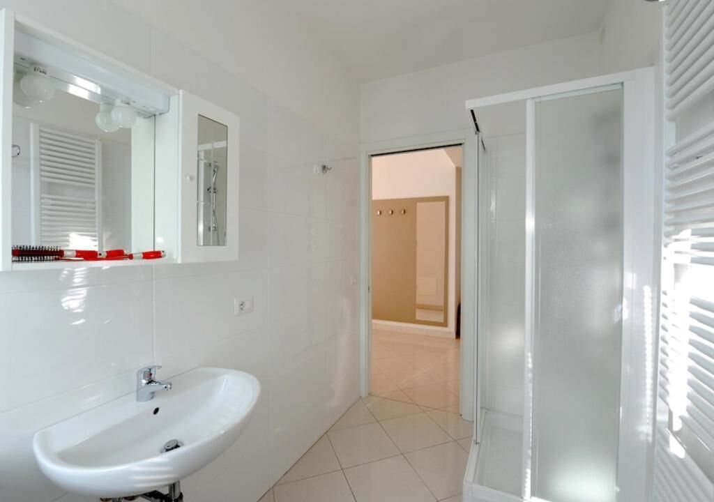 A bathroom with a white sink, a mirror, and a shower area.