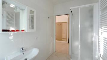 A bathroom with a white sink, a mirror, and a shower area.