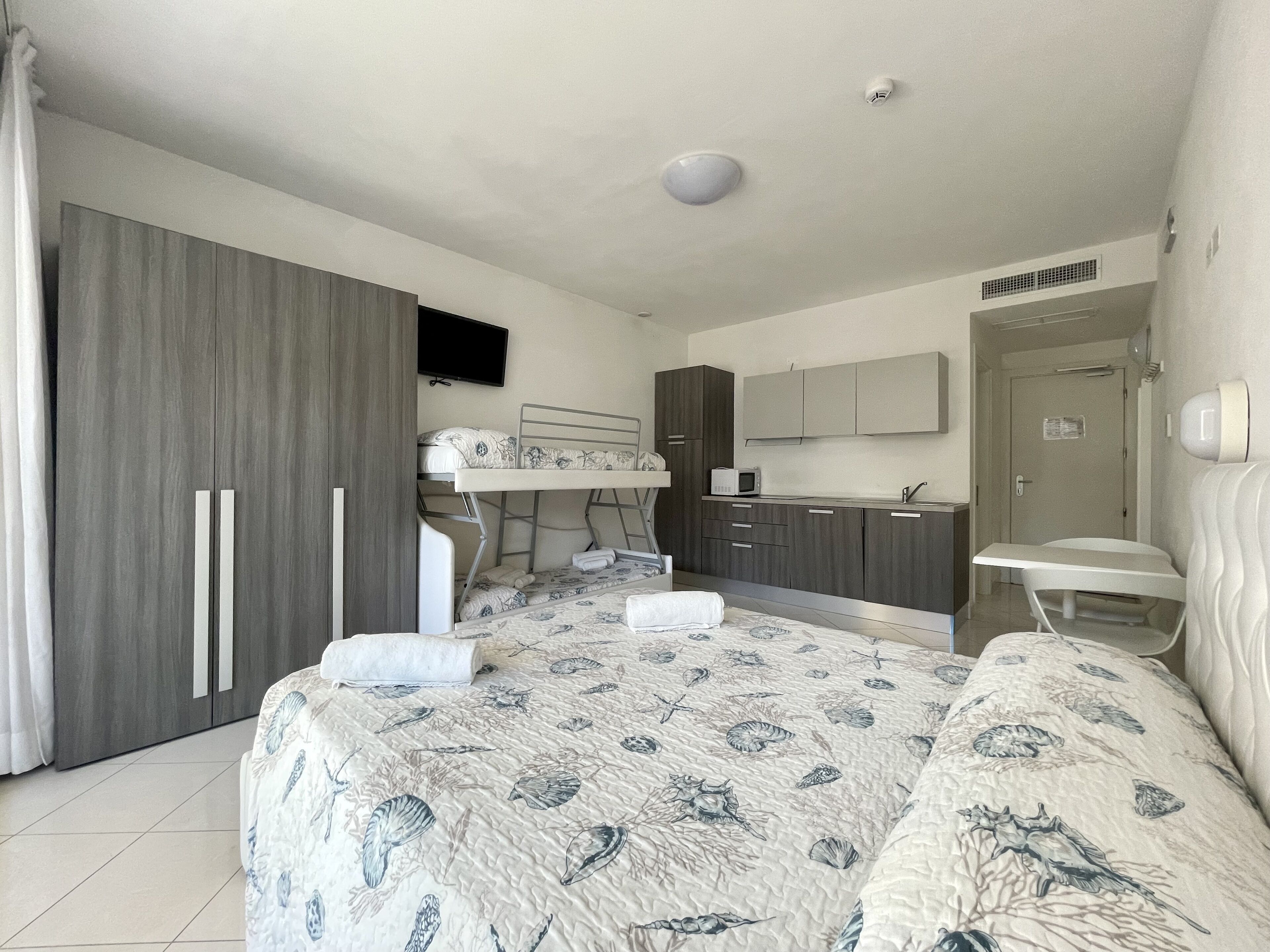 Une chambre avec un lit superposé, un bureau, un four à micro-ondes et un évier.